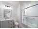 Bathroom featuring a gray vanity and toilet with a modern sliding glass shower and tub at 28419 Nc Hwy 73 Hwy, Albemarle, NC 28001