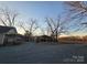 Gravel driveway leading to house with metal carport and large trees against a blue sky at 28419 Nc Hwy 73 Hwy, Albemarle, NC 28001