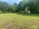 Large, grassy front yard leading to a cozy home nestled among mature trees, offering a serene and private setting at 28419 Nc Hwy 73 Hwy, Albemarle, NC 28001