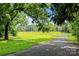 Picturesque property featuring a tree-lined drive and expansive green pasture under a bright blue sky at 28419 Nc Hwy 73 Hwy, Albemarle, NC 28001