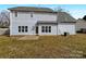 Backyard view of the home, featuring clean siding, a small patio, and a well-maintained lawn at 7829 Buddy Holly Rd, Charlotte, NC 28216