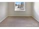 Bright bedroom featuring neutral walls, carpet, and a large window with a view of the neighborhood at 7829 Buddy Holly Rd, Charlotte, NC 28216