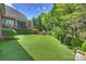Expansive backyard with lush artificial turf, tall trees, and manicured hedges for a private outdoor space at 100 Cliveden Ct, Belmont, NC 28012