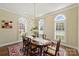Elegant dining room featuring a large wooden table, an ornate chandelier, and three arched windows with shutters at 100 Cliveden Ct, Belmont, NC 28012