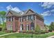 Traditional two-story red brick home with black shutters, well-manicured landscaping, and street sign at 100 Cliveden Ct, Belmont, NC 28012