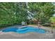 Backyard pool area featuring mature trees, brick accents, and garden views at 100 Cliveden Ct, Belmont, NC 28012