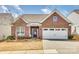 Charming red brick home featuring a two-car garage, manicured lawn, and complementary landscaping at 10014 Berkeley Castle Dr, Charlotte, NC 28273