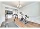 Open workout room featuring dark wood floors, a chandelier, a treadmill, and a stationary bike at 10014 Berkeley Castle Dr, Charlotte, NC 28273