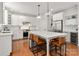 Bright kitchen with a center island, pendant lighting, white cabinets, stainless steel appliances, and hardwood floors at 11001 Valley Spring Dr, Charlotte, NC 28277