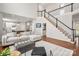 Open-concept living room showing the kitchen, stairs, a sectional sofa, and hardwood floors at 11001 Valley Spring Dr, Charlotte, NC 28277