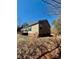 Side and back of beige home with green shutters and metal roof on a leaf covered lot at 191 Ashford Dr, Olin, NC 28660