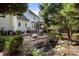 Lush backyard featuring a stone patio with a grill, a charming water feature, and mature trees at 19933 Scanmar Ln, Cornelius, NC 28031