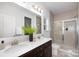 A modern bathroom features double sinks, a spacious mirror, and a glass-enclosed shower at 40189 Crooked Stick Dr # 1205, Lancaster, SC 29720