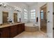 Bright bathroom featuring a large vanity, soaking tub, tiled shower, and natural light from the windows at 4336 Tottenham Rd, Charlotte, NC 28226