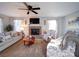 Cozy living room featuring a brick fireplace, comfortable seating, a ceiling fan, and natural light at 10929 Lassen Ct, Charlotte, NC 28214