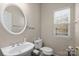 Cozy half bathroom featuring a pedestal sink and a window providing natural light at 11711 Royal Castle Ct, Charlotte, NC 28277