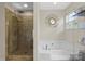 A bright bathroom features a glass-enclosed shower and soaking tub, complemented by elegant fixtures at 11711 Royal Castle Ct, Charlotte, NC 28277