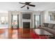 Comfortable living room featuring a fireplace, hardwood floors, ceiling fan, and large window at 11711 Royal Castle Ct, Charlotte, NC 28277