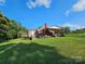 Expansive backyard featuring a covered patio area, mature trees, and lush green grass at 130 Scism Rd, Kings Mountain, NC 28086