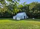 The side view of a white barn with a tin roof set against a backdrop of lush green trees at 130 Scism Rd, Kings Mountain, NC 28086