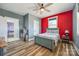 A bedroom with a colorful red accent wall and decor with natural light from the window at 13546 W Highway 55 W Hwy, York, SC 29745