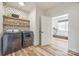 Well-lit laundry room featuring modern washer and dryer, floating shelves, and decorative wallpaper at 13546 W Highway 55 W Hwy, York, SC 29745