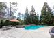 Serene in-ground pool surrounded by mature trees, an orange umbrella, and a white picnic table at 152 Bay Shore Loop, Mooresville, NC 28117