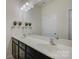 Bathroom with black vanity, double sinks, and large mirror with decorative accents at 15237 Red Canoe Way, Charlotte, NC 28278