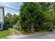 Exterior view of home showing gravel driveway and mature landscaping with shade trees at 1716 Umstead St, Charlotte, NC 28205