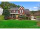 Charming two-story red brick home with manicured lawn and lush landscaping at 204 Silvercliff Dr, Mount Holly, NC 28120