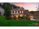Charming two-story red brick home at dusk with manicured lawn and lush landscaping at 204 Silvercliff Dr, Mount Holly, NC 28120