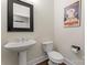 Elegant powder room featuring a pedestal sink, toilet, and decorative mirror at 204 Silvercliff Dr, Mount Holly, NC 28120