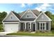 Charming gray home with a covered front porch, manicured lawn and neatly arranged landscaping at 2208 Indigo Branch Rd, Indian Land, SC 29707