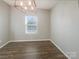 Bright, empty dining room with hardwood floors, a modern light fixture, and a view of the front yard at 23186 Goose Down Ln, Lancaster, SC 29720