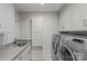 Bright laundry room features stainless steel washer and dryer, gray counters, and white cabinetry at 2419 Lemon Tree Ln, Charlotte, NC 28211