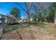 An exterior shot of a backyard with a partial fence, complemented by green grass and mature trees at 4211 Seaforth Dr, Charlotte, NC 28205