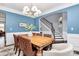 Open-concept formal dining room featuring blue accent wall and stairway to second level at 5019 Mill Creek Rd, Clover, SC 29710