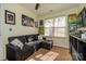 Cozy carpeted bedroom featuring a dark sofa, bright window and decorative artwork at 8422 Chaceview Ct, Charlotte, NC 28269