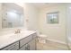 Bathroom with white vanity, large mirror, and a toilet next to a window at 8624 Sharonbrook Dr, Charlotte, NC 28210