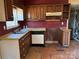 A partially disassembled kitchen featuring vintage cabinets, a brick wall and an old dishwasher at 1406 Ratchford Dr, Dallas, NC 28034