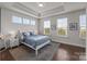 Bright bedroom featuring a tray ceiling, wood floors, and several windows at 1037 Naples Dr, Davidson, NC 28036