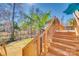 Wooden stairs lead to a spacious deck, surrounded by trees and palm fronds in this home's backyard at 125 Rocky Trail Ct, Fort Mill, SC 29715