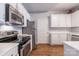 Well-lit kitchen with stainless steel appliances, white cabinets, and laminate floors at 14941 Santa Lucia Dr, Charlotte, NC 28277