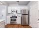 Modern kitchen with stainless steel appliances, white cabinets, and laminate floors at 14941 Santa Lucia Dr, Charlotte, NC 28277