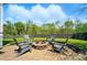 Backyard features a stone firepit, surrounded by gray Adirondack chairs, on a patio made of stone pavers at 15307 Country Lake Dr, Pineville, NC 28134