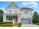 Charming two-story home with gray siding, an orange front door, a covered porch, and a two-car garage at 15307 Country Lake Dr, Pineville, NC 28134