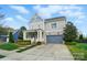 Charming two-story home with gray siding, an orange front door, a covered porch, and a two-car garage at 15307 Country Lake Dr, Pineville, NC 28134