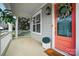 Inviting front porch with a brick floor, white railing, and a vibrant orange front door with a wreath at 15307 Country Lake Dr, Pineville, NC 28134