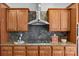 Close up of a cooktop with stainless steel hood and wood cabinets with dark backsplash at 2464 Chatham Dr, Indian Land, SC 29707