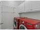The laundry room with red washer and dryer, white cabinets and shelving at 2464 Chatham Dr, Indian Land, SC 29707